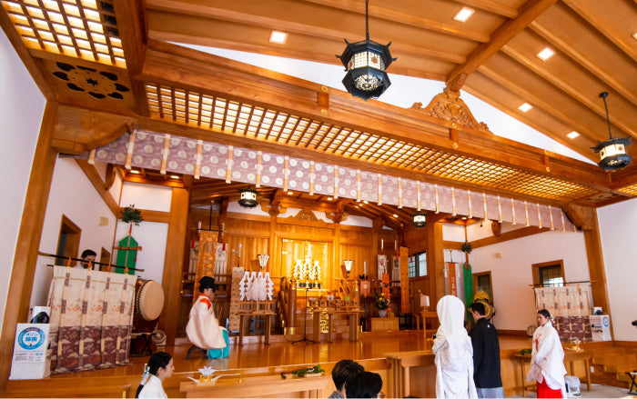 Interior of a Shinto shrine main hall during a wedding ceremony, showing the ceremonial space and architecture
