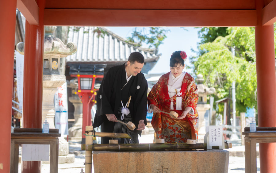 Bride and groom purifying their hands at the temizuya water basin before a Shinto wedding ceremony