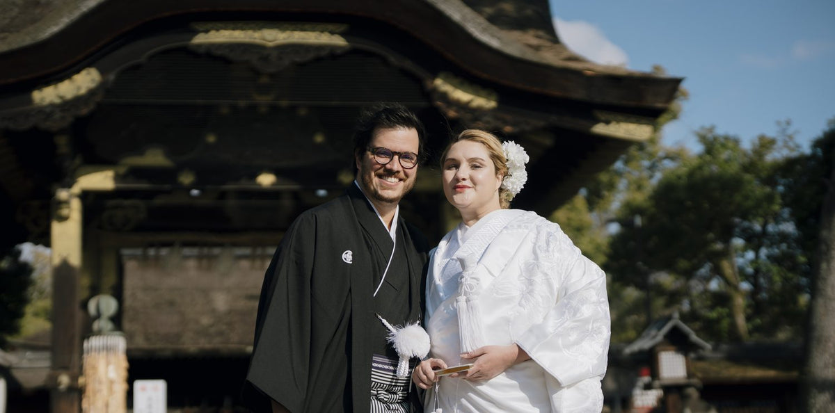 A couple from Brazil in montsuki and shiromuku smiling before the karamon gate of Toyokuni Shrine, Kyoto