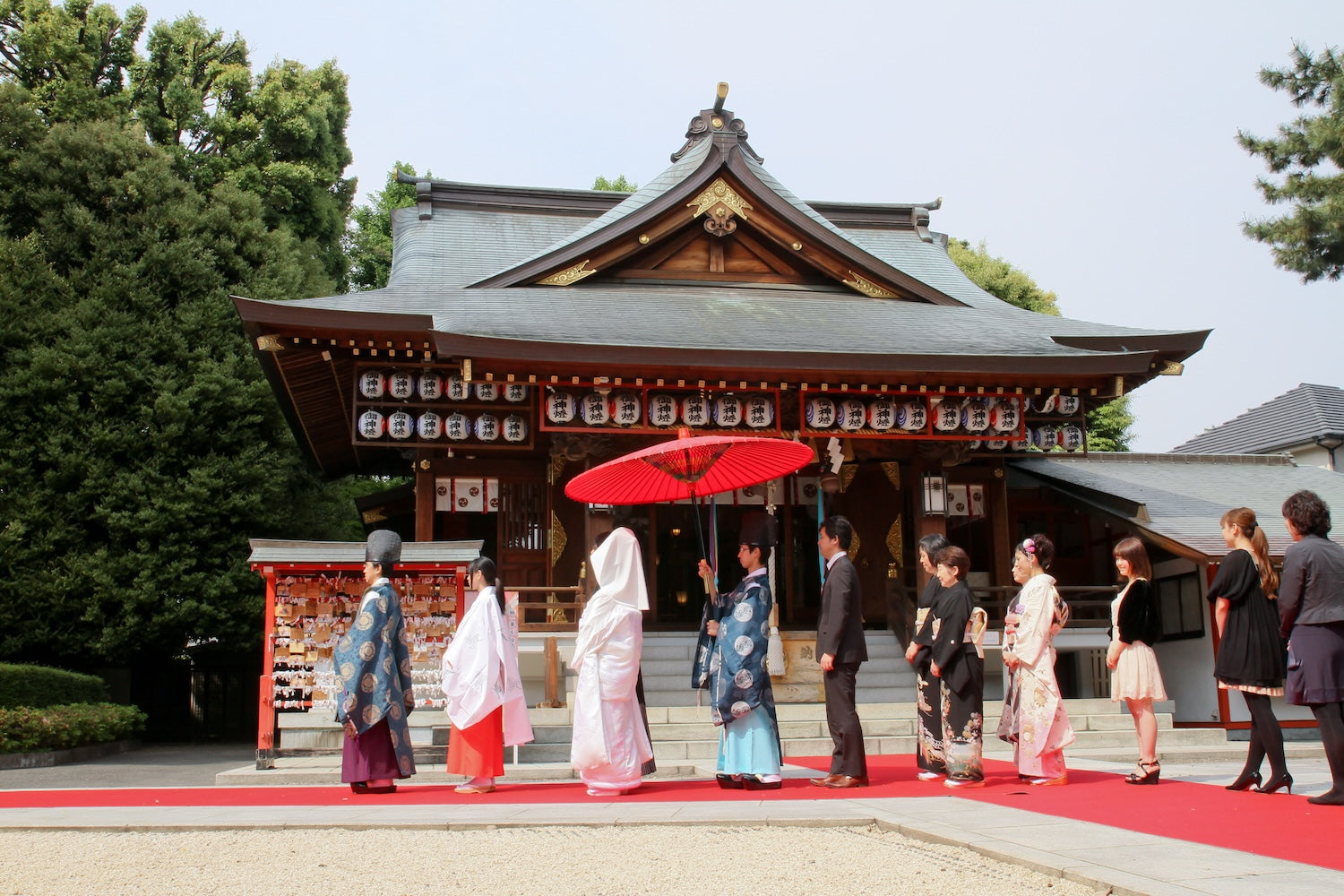 Wedding procession along a red carpet with family and guests at the shrine