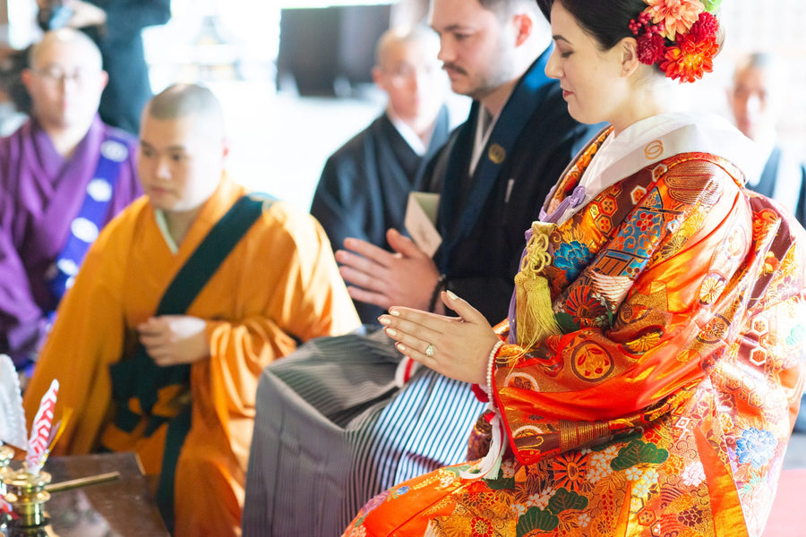 The bride joining her hands in prayer beside a monk during the Buddhist wedding ceremony