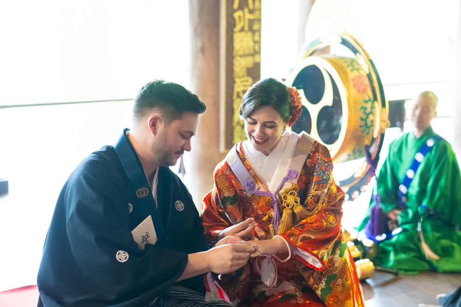 The couple exchanging rings during the Buddhist ceremony, monks behind them