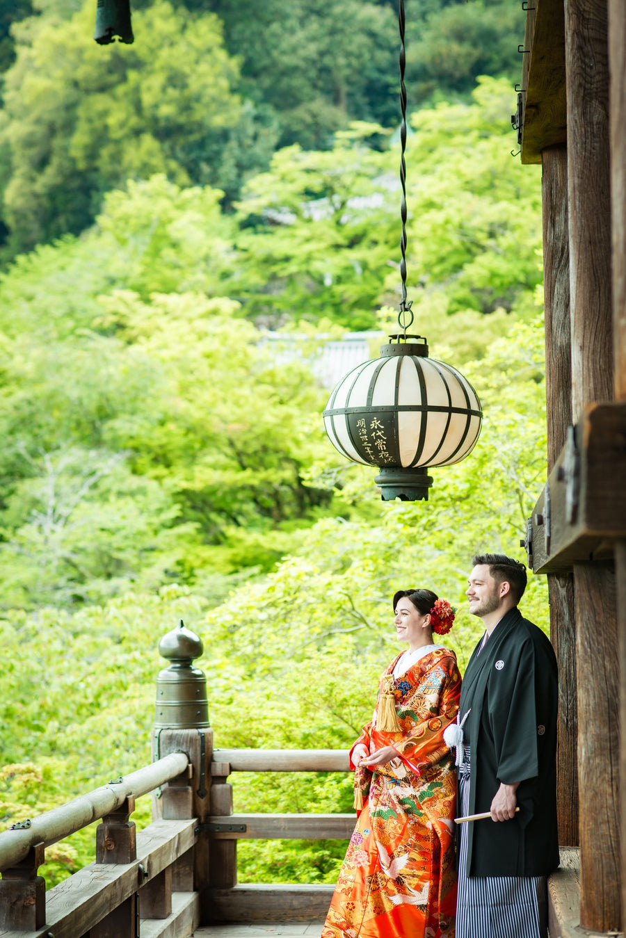 The couple on the stage of Hasedera, a hanging lantern and green maples around them