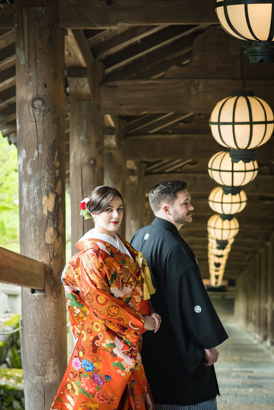 The couple facing each other in the long corridor of Hasedera, lanterns overhead