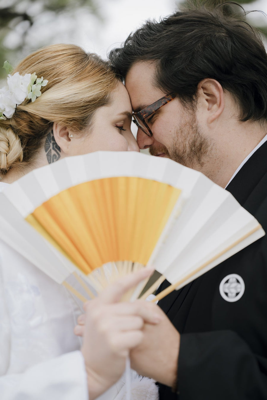 The couple close together, holding a folding fan, in the shrine garden