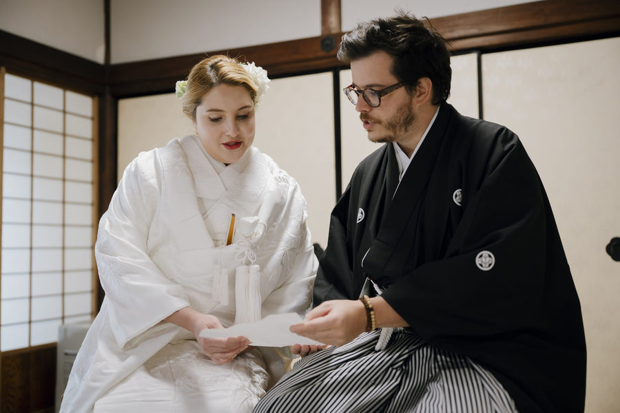 The couple seated indoors, practicing their wedding vows in Japanese from a written sheet