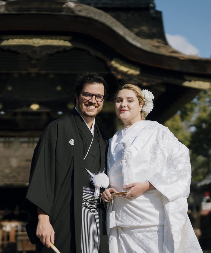 A couple from Brazil in montsuki and shiromuku smiling before the karamon gate of Toyokuni Shrine, Kyoto
